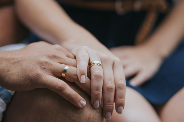 two hands with matching couple’s wedding rings