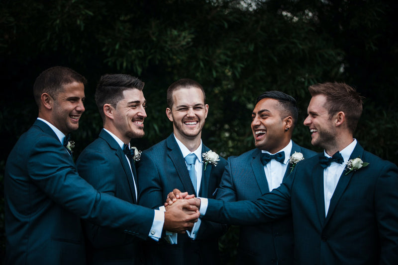 a groom standing with his groomsmen smiling