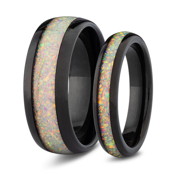 Two black rings with opal inlay on a white background