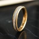 Gold opal ring with a textured band on a dark reflective surface