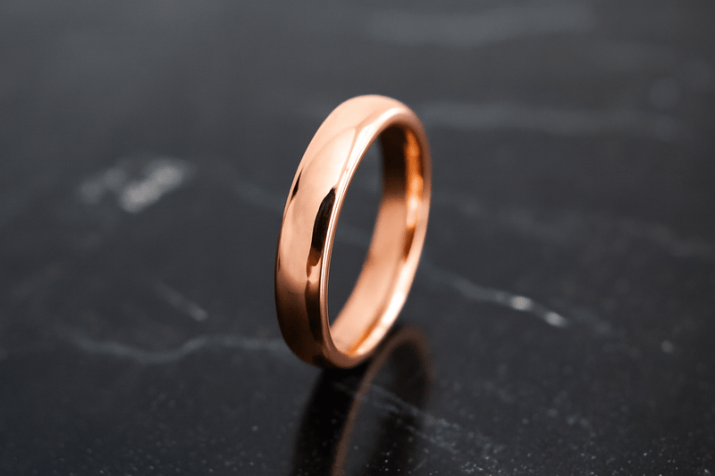 Rose gold womens wedding band on black surface