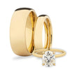 Two his and hers gold wedding bands with an oval diamond solitaire on a white background