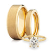 Two gold wedding bands with a solitaire diamond engagement ring on a white background