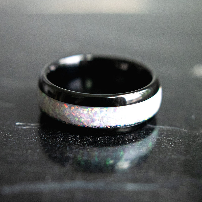 opal wedding band with black trim lying on its side