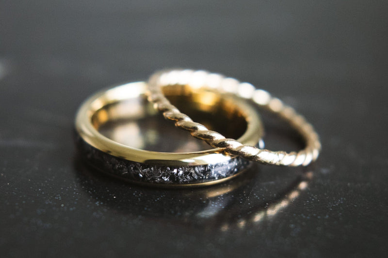 Sideways view of a women's gold and meteorite wedding band and a thinner band