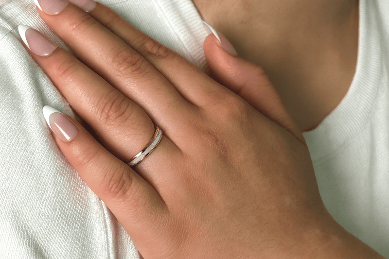 an opal ring with a gold band on a woman’s hand