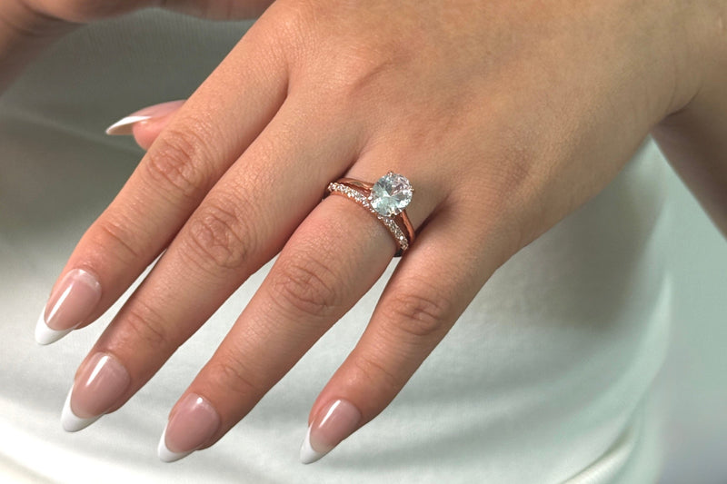 Woman’s hand wearing a stack with the Bella Rose gold oval engagement ring 