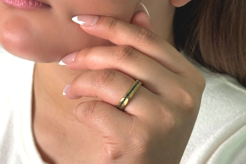 a woman wearing a gold hammered wedding band on her hand